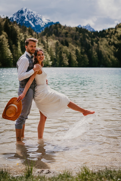 Pure Freude beim Brautpaar im kalten Bergsee vor Alpenpanorama